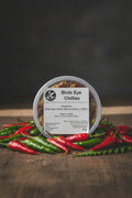 Container of Birds Eye chilies with a label on a rustic background