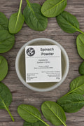 Spinach powder in a container with a label on a rustic background