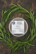 Container of ground tarragon with a label on a rustic background